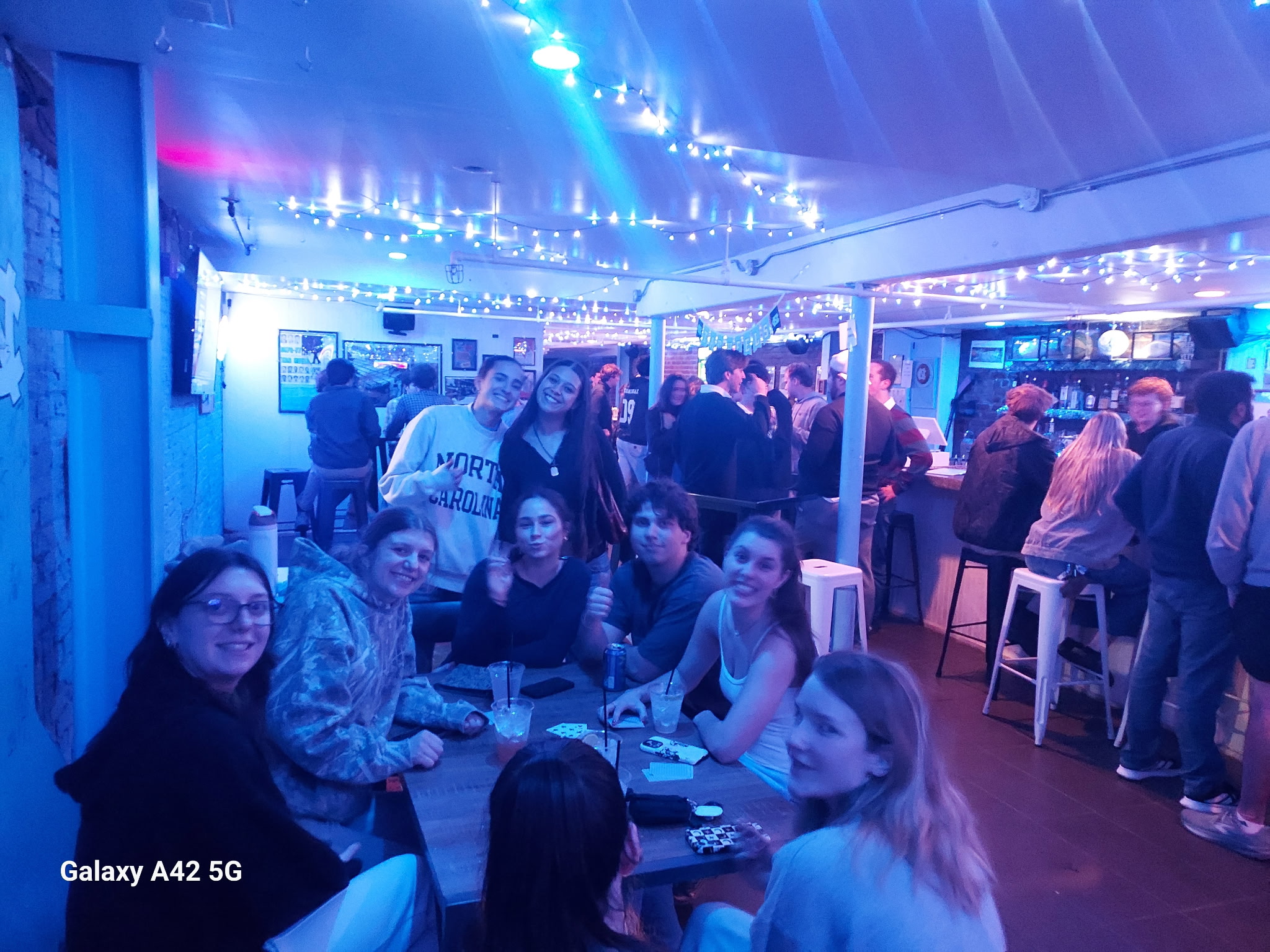 Friends gathered around a table at Max's Tin Can under string lights