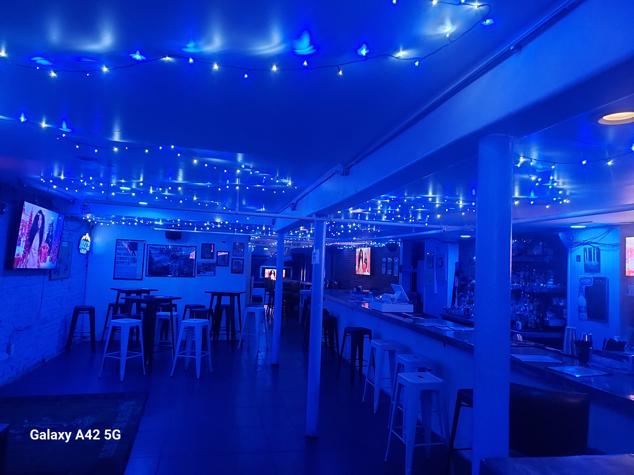 The Max's Tin Can bar and stools glowing blue beneath string lights